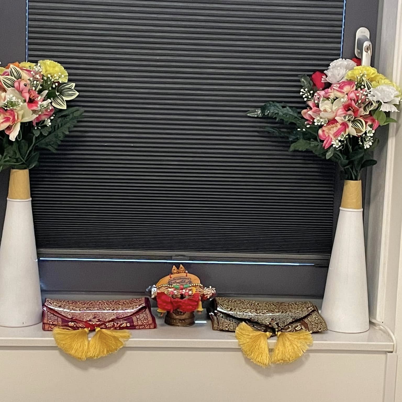 Vensterbank met twee vazen bloemen, Thaise versieringen en gele kwasten